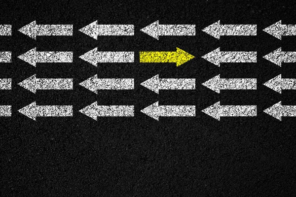 Going your own way concept. Yellow arrow in the opposite direction among white on black background.