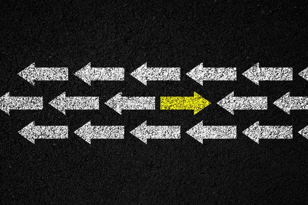 Going your own way concept. Yellow arrow in the opposite direction among white on black background.