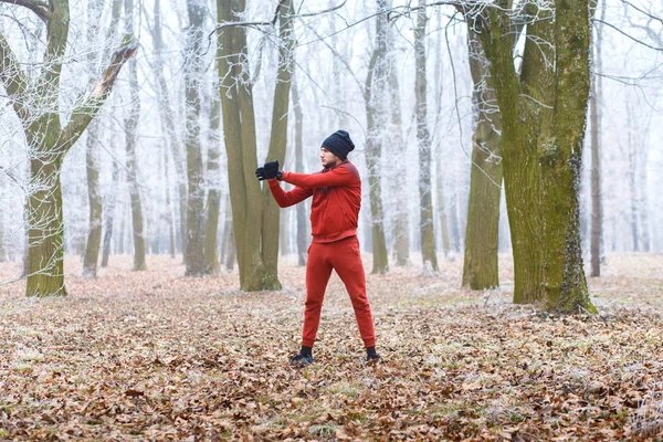 Young male jogger warming up before running outdoors in winter