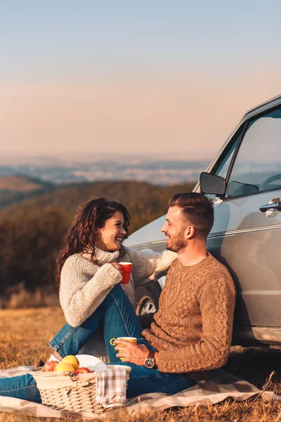 young couple have a picnic near the car in the mountains