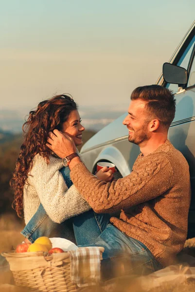 young couple have a picnic near the car in the mountains