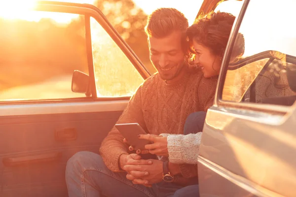 Beautiful couple on road trip, they are taking a break from driving and looking for direction on tablet