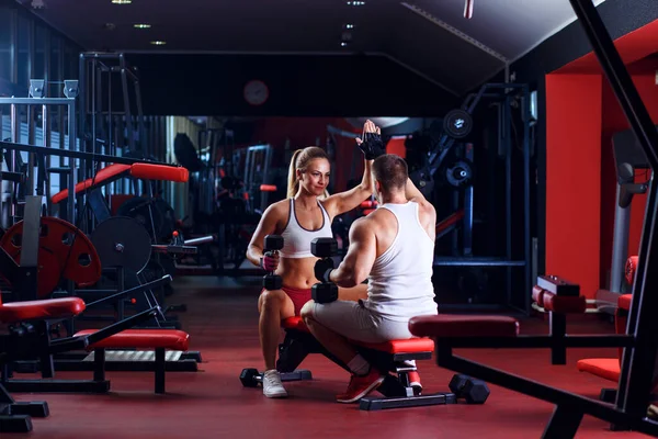 Young couple exercising with weight in the gym.
