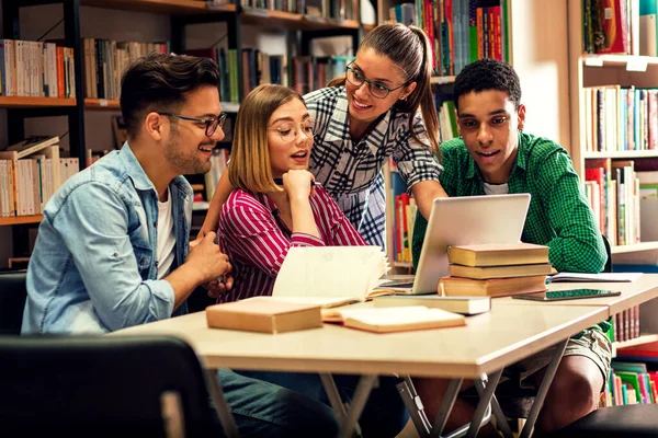 Four young students study in the school library, they using laptop for researching online.