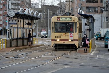 Hokkaido, Japonya - 14 Nisan 2016: Eski klasik klasik kırmızı tramvay treni Hakodate City, Japonya 'da bir istasyonda yolcu almak için duruyor.