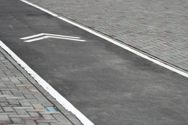 Señal de bicicleta blanca con flecha en el asfalto, señal de carretera en bicicleta en la calle, señal de carril bici en la calle, fondo gris — Foto de Stock