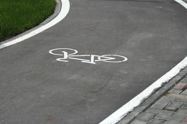 White bicycle sign with arrow on the asphalt, bike road sign on the street, bicycle lane sign on street, gray background