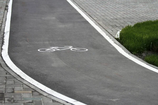 White bicycle sign with arrow on the asphalt, bike road sign on the street, bicycle lane sign on street, gray background