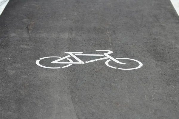 White bicycle sign with arrow on the asphalt, bike road sign on the street, bicycle lane sign on street, gray background