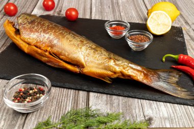  Baharat ve sebzelerle dolu bir tahtada füme balık.