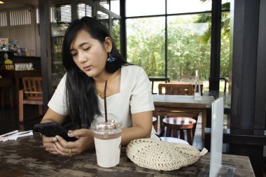 Taylandlı kadın rahat smartphone oynamak ve üzerinde 13 Kasım 2018: Saraburi, Thailand içinde frappe kahve dükkanında çikolata içme otururken