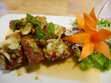 Baharatlı salata plaka restoran Nonthaburi, Tayland masada üzerinde kızarmış domuz yedek kaburga sarımsak ve biber ile karıştırın