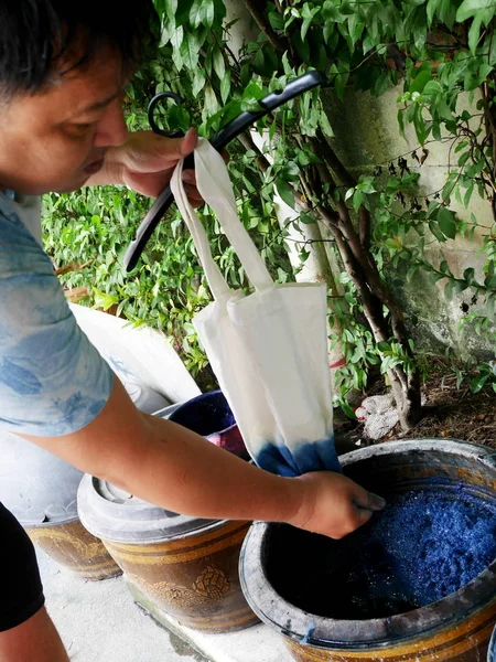 Thai men tie batik dyeing Indigenous Knowledge of Phrae people is Chemical and liquid dye Mauhom color in pot of Traditional clothes Kind of fashion in Northern Thailand at Nonthaburi, Thailand.