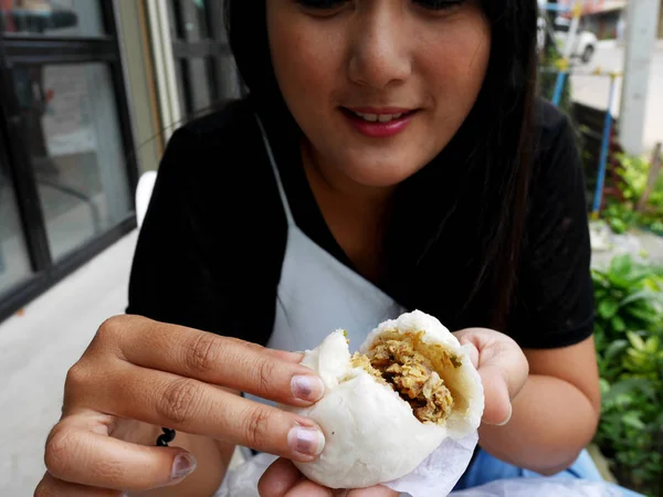 Thai women holding and show Kind of Chinese snacks steamed stuff buns before eat at outdoor of cafe and local restaurant in Bangkok, Thailand