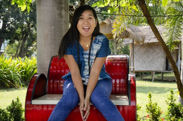 アジアのタイの女性の旅行を訪問し 歌うブリ タイの公共公園で写真を撮るポーズ赤の金属のベンチの上に座って — ストック写真