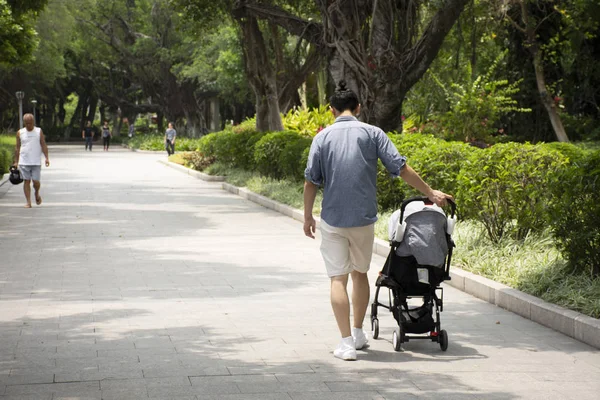 庭の道路にカートと赤ちゃんを押す中国人の人々 — ストック写真