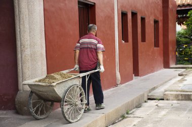 Çinli yaşlı adamlar sepeti çekerek kum taşımak şantiyeye gitmek 