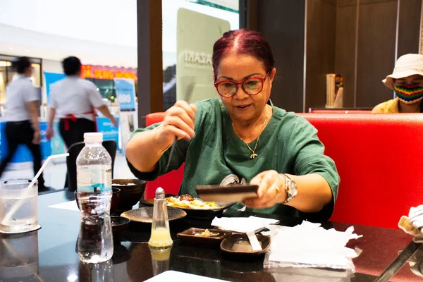 Thai women senior people eat and drink japanese food set cooking fried meat and vegetables donburi with miso soup and seasoning at restaurant in Bangkok, Thailand