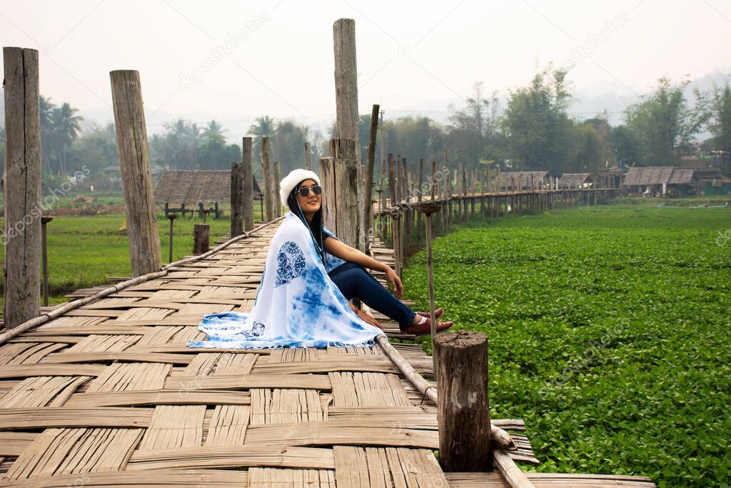 Travelers thai women wearing indigo shawl travel visit and sit on Su Tong Pae bamboo wooden bridge for take photo at Phu Sa Ma temple while PM 2.5 Dust situation at Pai city in Mae Hong Son, Thailand