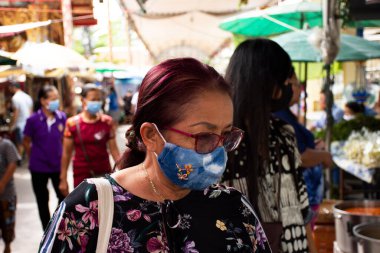 Seyahat pazarı için kumaş maske takan ve dua eden Buda 'ya saygı duyan Taylandlı yaşlı anne 12 Temmuz 2020' de Tayland 'ın Samut Prakan kentinde Wat Bang Phli Yai Nai Tapınağında 19 salgını patlak verdi.