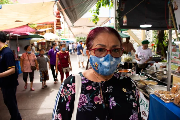 Seyahat pazarı için kumaş maske takan ve dua eden Buda 'ya saygı duyan Taylandlı yaşlı anne 12 Temmuz 2020' de Tayland 'ın Samut Prakan kentinde Wat Bang Phli Yai Nai Tapınağında 19 salgını patlak verdi.