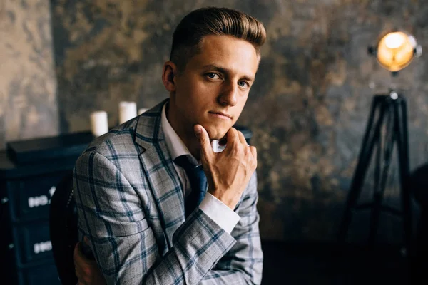 Confident young man in elegant suit is looking at camera