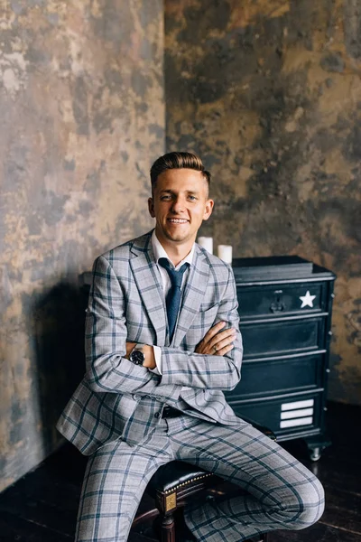 A man in a blue suit is sitting on a chair