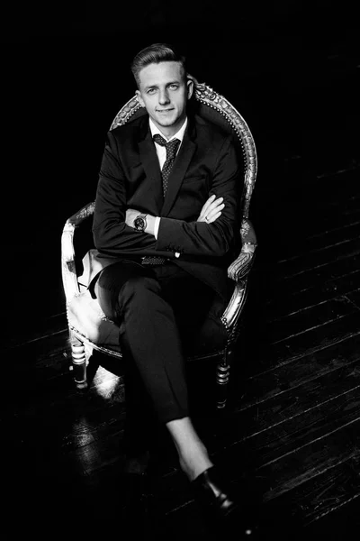 Элегантный мужчина сидит на стуле в студии — стоковое фото