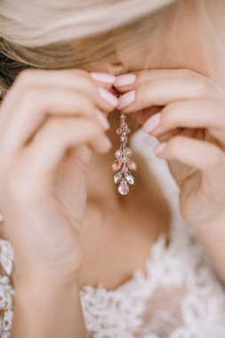 Zarif sarışın gelin küpe closeup koyarak, hazırlanıyor 