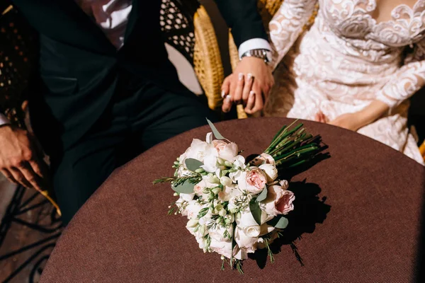 Novios en un café. El ramo de boda sobre la mesa en la resta —  Fotos de Stock