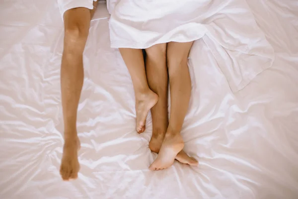 Τα πόδια του ανθρώπου και της γυναίκας σε λευκό φύλλο κρεβάτι μερικώς καλυμμένο β — Φωτογραφία Αρχείου