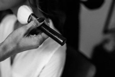 makyaj fırçası tutan stilist ve genç gelin kapalı oturan kırpılmış çekim, siyah beyaz fotoğraf