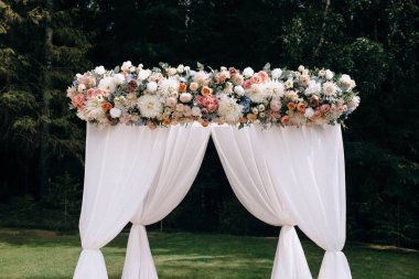 açık düğün töreninde beyaz kumaş ve çiçeklerle süslenmiş güzel düğün kemeri 