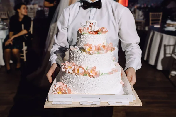 cropped shot of waiter holding beautiful festive cake at wedding reception
