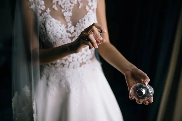 屋内に香水瓶を保持する白いウェディングドレスで若い花嫁のトリミングショット — ストック写真