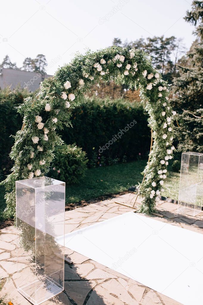 beautiful wedding arch decorated with flowers and green leaves for outdoor wedding ceremony