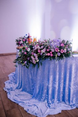 düğün resepsiyonda mavi masa örtüsü ile masada güzel ihale pembe ve mor çiçekler