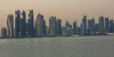  Doha Katar gün ışığında gökdelenler, ağaçlar, bulutlar ve gökyüzü ile önplanda Arap körfezini gösteren gökyüzü..