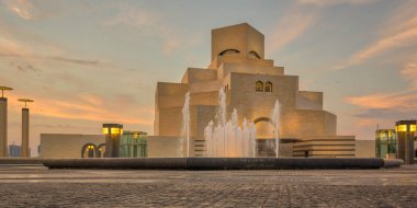 İslam Sanatları Müzesi, Doha, Katar gün ışığında dış görünüşü ön planda çeşme ve arka planda bulutlar