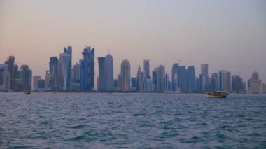 Doha ufuk çizgisi Cor niche günbatımı çekimini gösteriyor. Arap Körfezi 'nin ön planında çam ağaçları var.