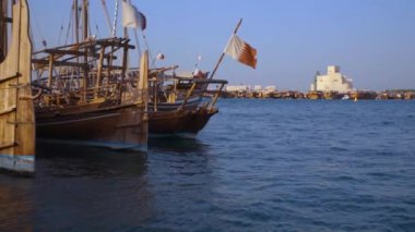 Doha Corniche, Arap Körfezi 'nde Dhows' u ön planda Katar bayrağı dalgalanırken ve arka planda İslam Sanatları Müzesi varken gösteriyor.