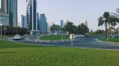 Gün batımında Doha Cor-niche 'de Sheraton Parkı' nı, Dallah kahve demliği heykelini, caddelerde ve Batı Körfezi gökdelenlerinde hareket eden arabaları gösteriyor.