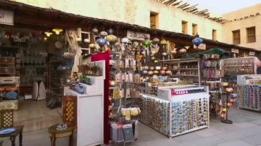 Souq Waqif Doha Qatar ana caddesinde güneş batarken Corona virüsü salgını sırasında yüz maskesi takan insanların olduğu geleneksel Antika ve Sanat Dükkanlarını gösteriyor. Katar iş için yeniden açılıyor