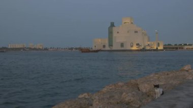 İslam Sanatları Müzesi Doha Katar dış gün batımı Doha Corniche 'den ön planda Arap körfezinde tekne ve arka planda ufuk çizgisi ile çekim