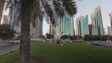 Doha Corniche, Sheraton Parkı 'ndan gün ışığında yürürken kahve demliği heykelini (Dallah), caddelerde ve batı körfezi gökdelenlerinde hareket eden arabaları gösteriyor.