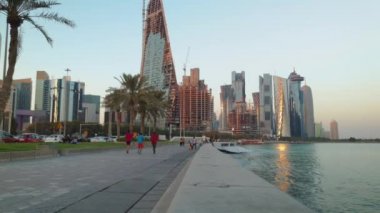 Doha Katar 'da Doha Corniche öğleden sonra çekilen fotoğrafta insanlar yürüyor, koşuyor, Arap Körfezi' nde Dhow ve Doha ufuk çizgisi etkin bir şekilde zum yapıyor. 