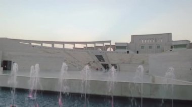 Doha Katar 'daki Katara Kültür Köyü öğleden sonra Amphitiyatrosu, renkli çeşme ve Doğanın Gücü 2 heykelinin çekimini gösteriyor.