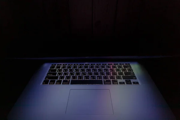 The light from the laptop screen is ajar in the dark