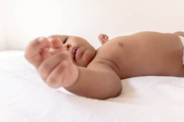 Yeni doğmuş bir bebek beyaz bir yatakta yatıyor.