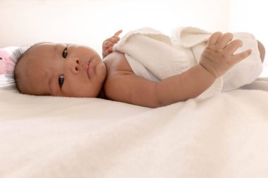 Yeni doğmuş bir bebek beyaz bir yatakta yatıyor.